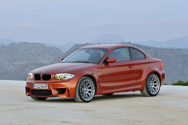 Orange Pkw bmw 1m auf dem Hintergrund der Berge