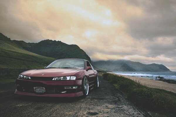 Ein weinroter Nissan am Meer