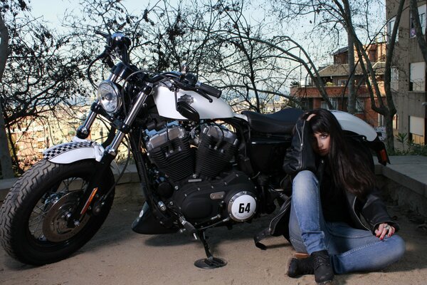 Jeune fille assise dans la rue près de la moto