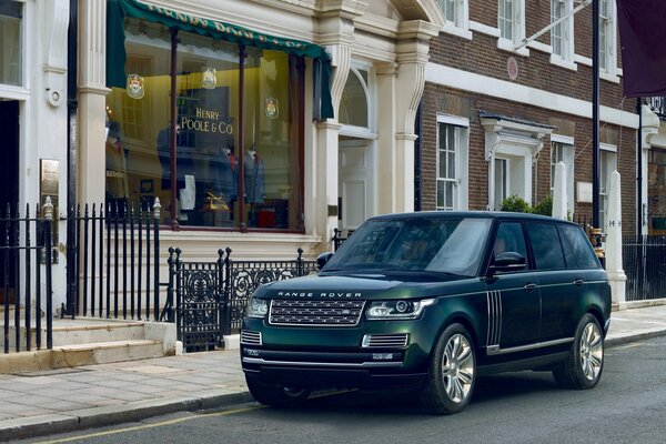 Land rover of dark emerald color on the urban landscape