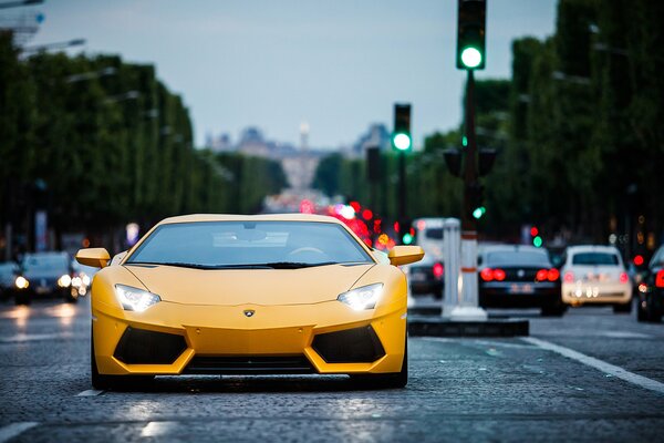 Yellow Lamborghini front view, with headlights on the road