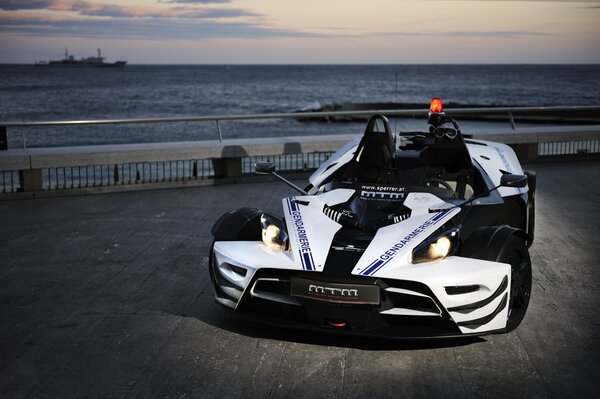 Voiture de sport blanche au bord de la mer le soir