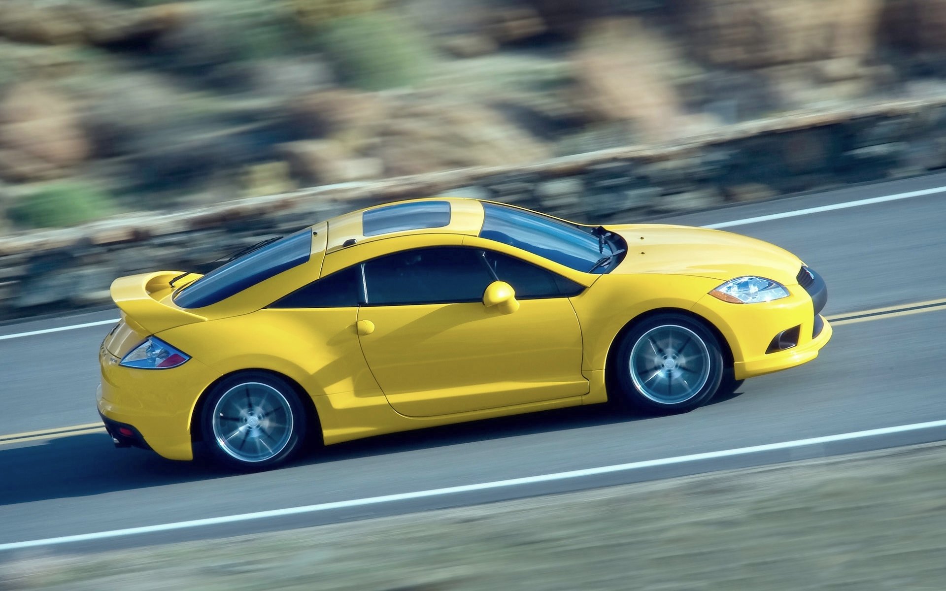 mitsubishi eclipse auto amarillo vista lateral en movimiento