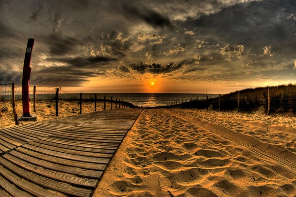 A path on the beach leads to the sunset on the sea
