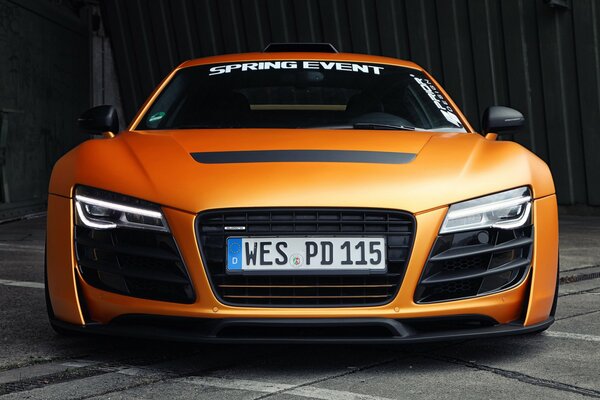 Ein orangefarbenes Auto der Marke audi mit Blick auf die Scheinwerfer vorn