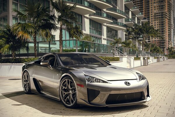 Silver Lexus supercar on the background of a house with palm trees on the cobblestones