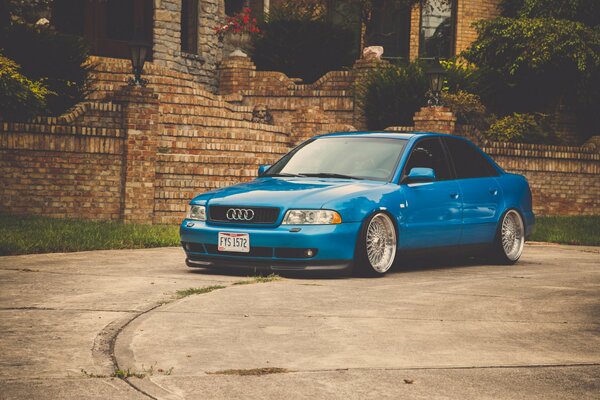 Audi A4 azul frente a la valla de ladrillo