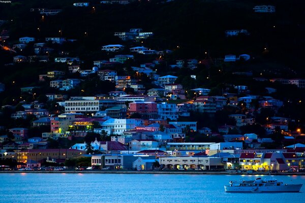 The ship sails along the shore near the houses