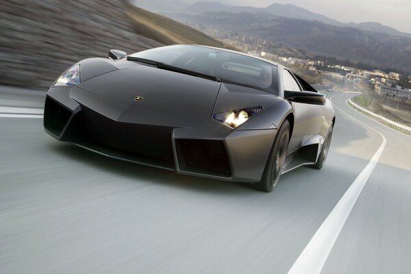 Lamborghini, city in the distance behind, speed, mountains, highway from the city, hood