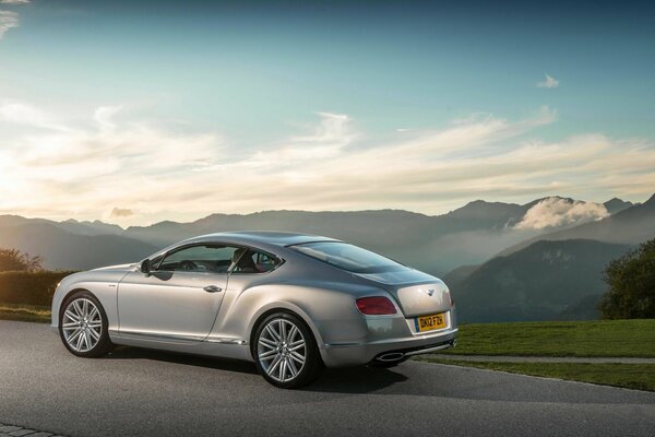 Bentley grigia su ruote modellate sullo sfondo delle montagne