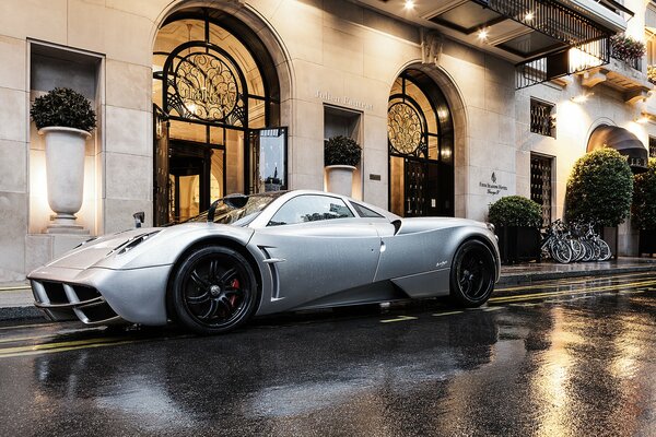 A picture of a white pagani huayra car parked outside the building