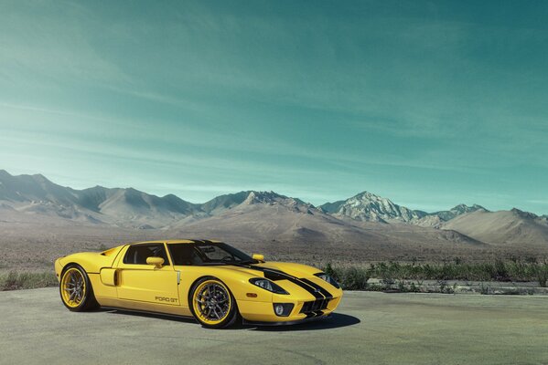 Jaune avec deux bandes noires, le long de la surface de la carrosserie, Ford GT se dresse sur fond de montagnes