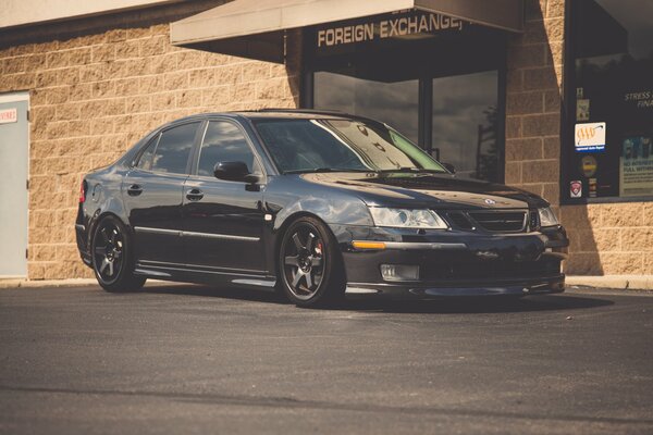 Black saab on the background of a brick store