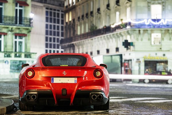 Ein rotes Ferrari-Auto steht vor dem Hintergrund von Gebäuden