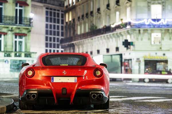 A red Ferrari car stands against the background of buildings