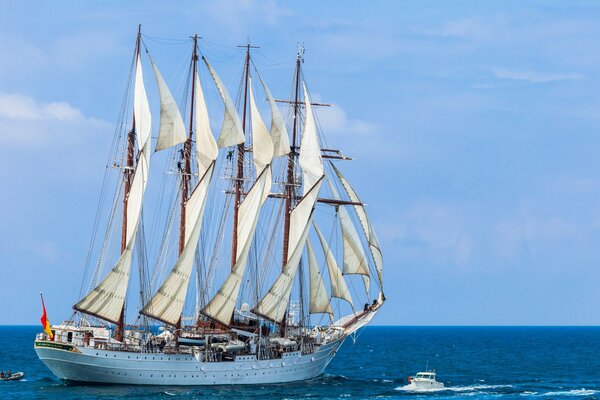 Ein weißes Segelboot und ein kleines Boot im Meer