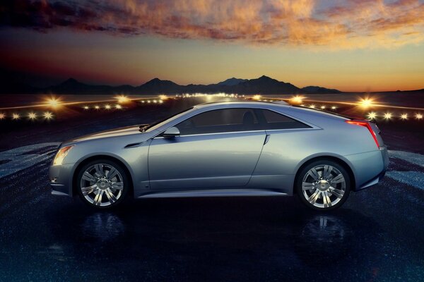 Hermoso coche gris Cadillac en el fondo de la puesta de sol