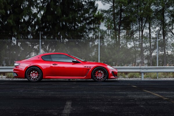 L auto rossa del marchio Maserati si trova su una pista recintata