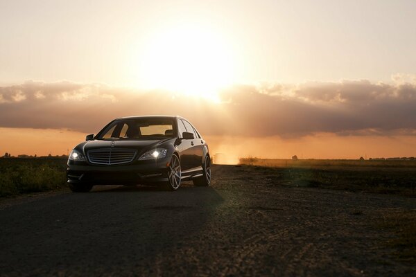 Strict Mercedes on the background of clouds and the setting sun in the field