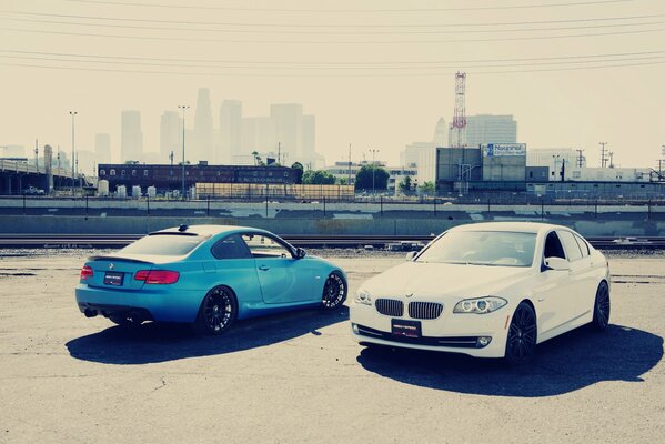 Two cars are standing nose to nose waiting for the owners a man and a woman