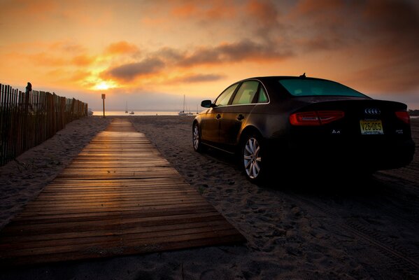 Sunrise on the beach and a standing car on the sand