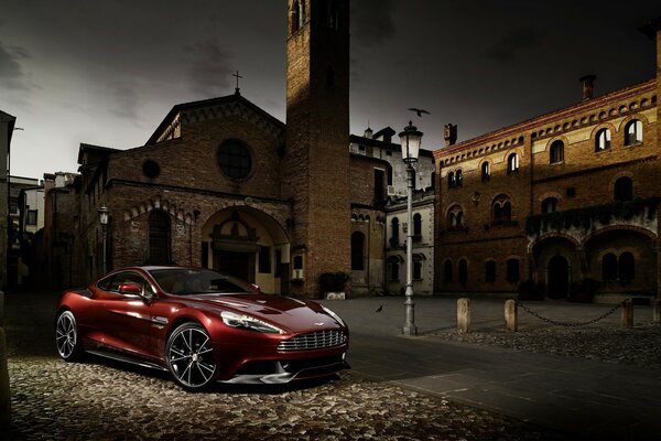 Red aston martin m310 car in a dim courtyard