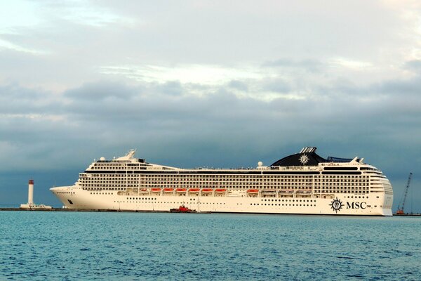 Cruise ship in the water on the background of a lighthouse