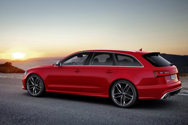 Red Audi station wagon on the background of sunset on the road