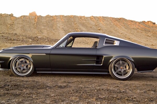 Black sports car mustang on the sand in the mountains