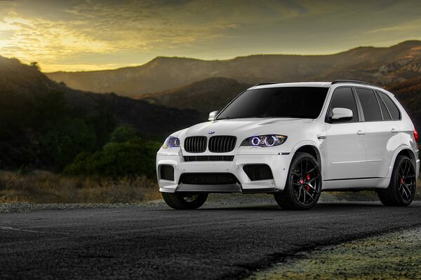 Un BMW blanc sur la route le long des montagnes