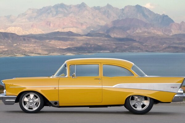 Yellow retro car in the mountains near the lake