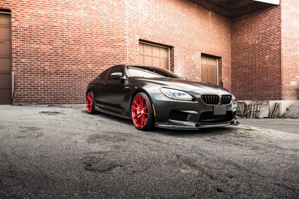 Black BMW coupe on the background of a red brick building