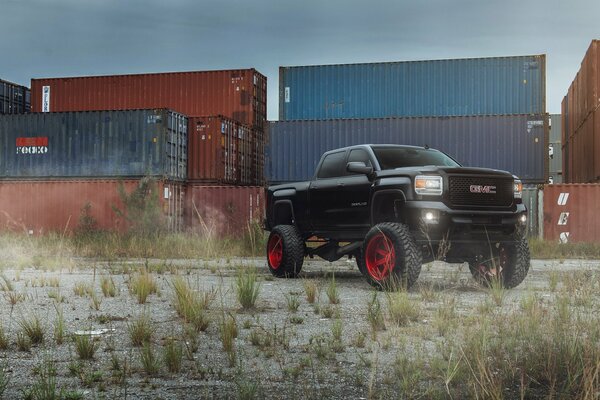 Pick-up noir avec tuning sur fond de conteneurs