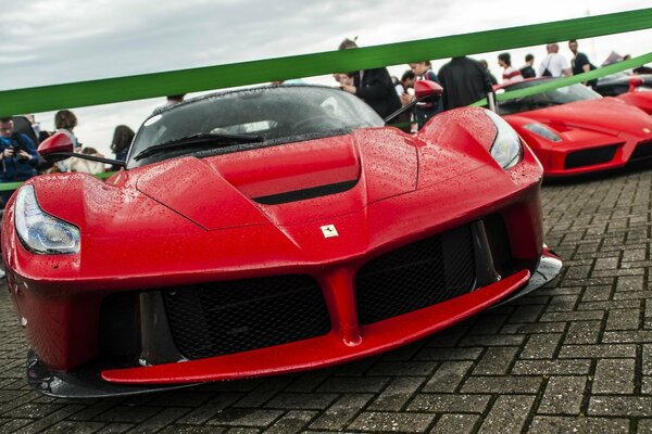 Une supercar Ferrari rouge exposée sous la pluie