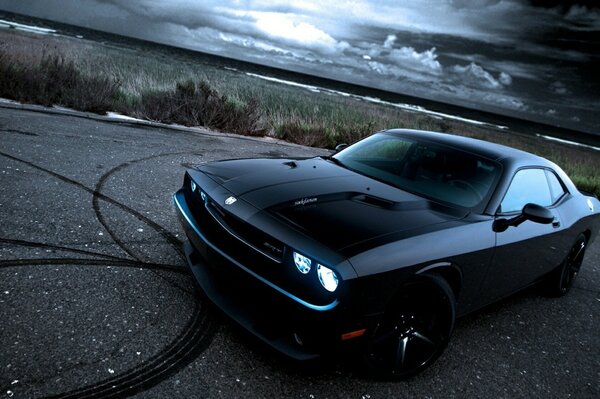 Negro guapo dodge challenger después de la deriva en la carretera