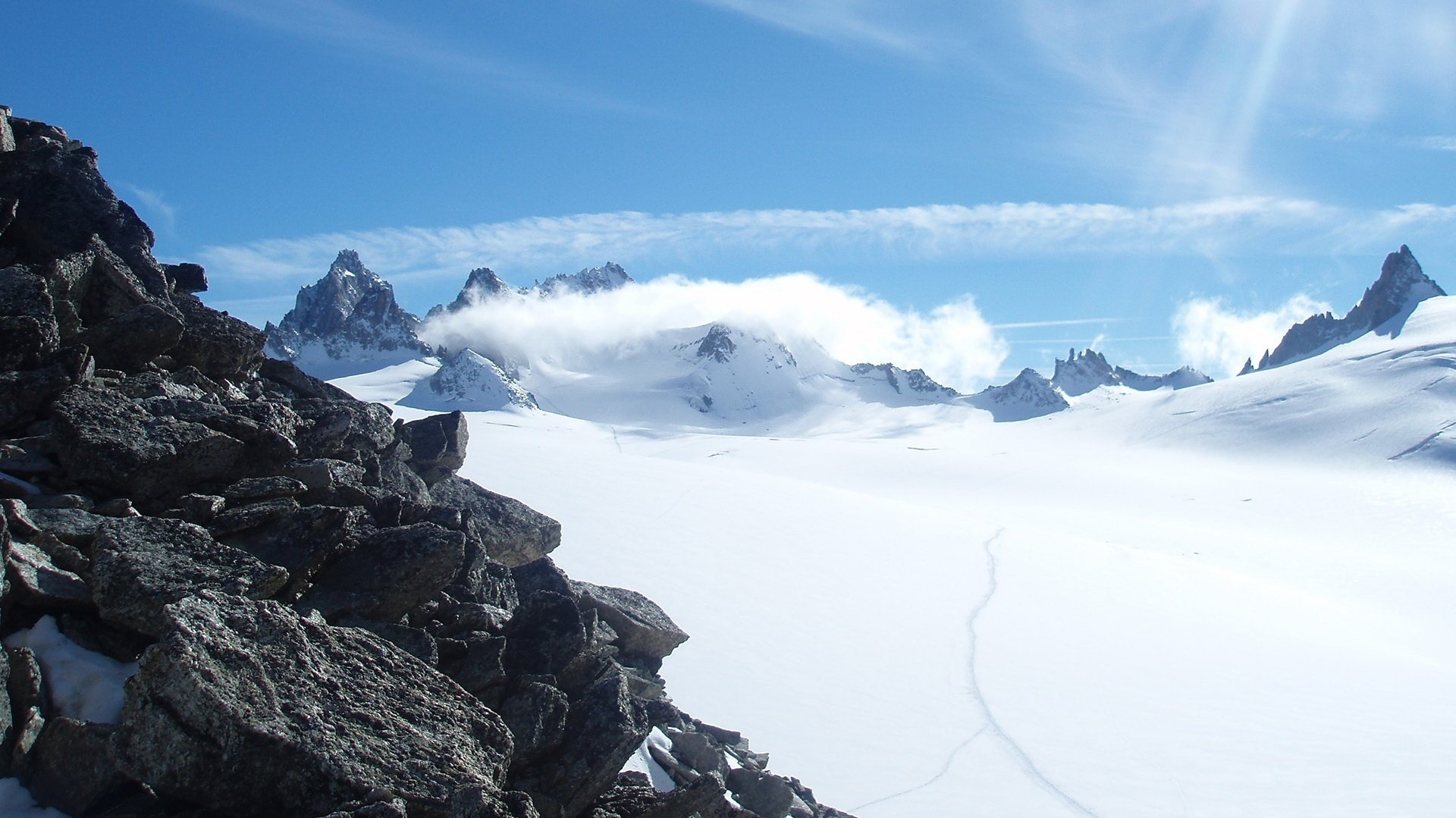 pierres de montagne grises tapis de neige passerelle montagnes neige paysage congères vue gel vent couche nuages