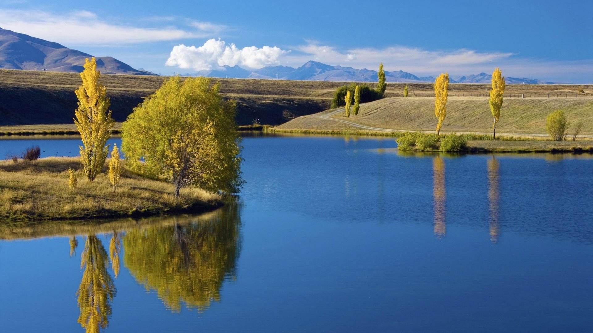 wyspa jesienna pora niebieska woda woda niebo jezioro chmury odbicie drzewa wzgórza natura krajobraz wczesna jesień