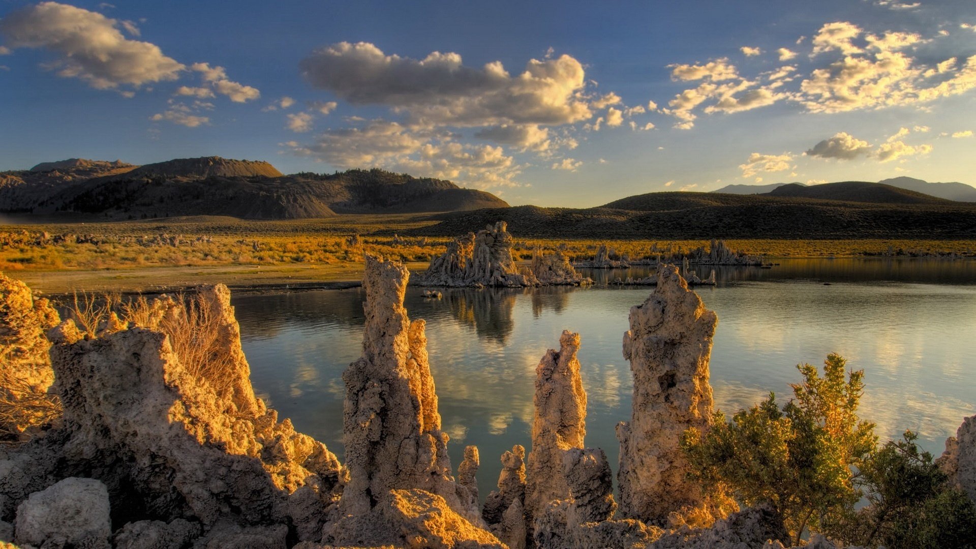 and mound the lake in the field shape mirror mountains water the sky reflection clouds hills nature the sun pond landscape