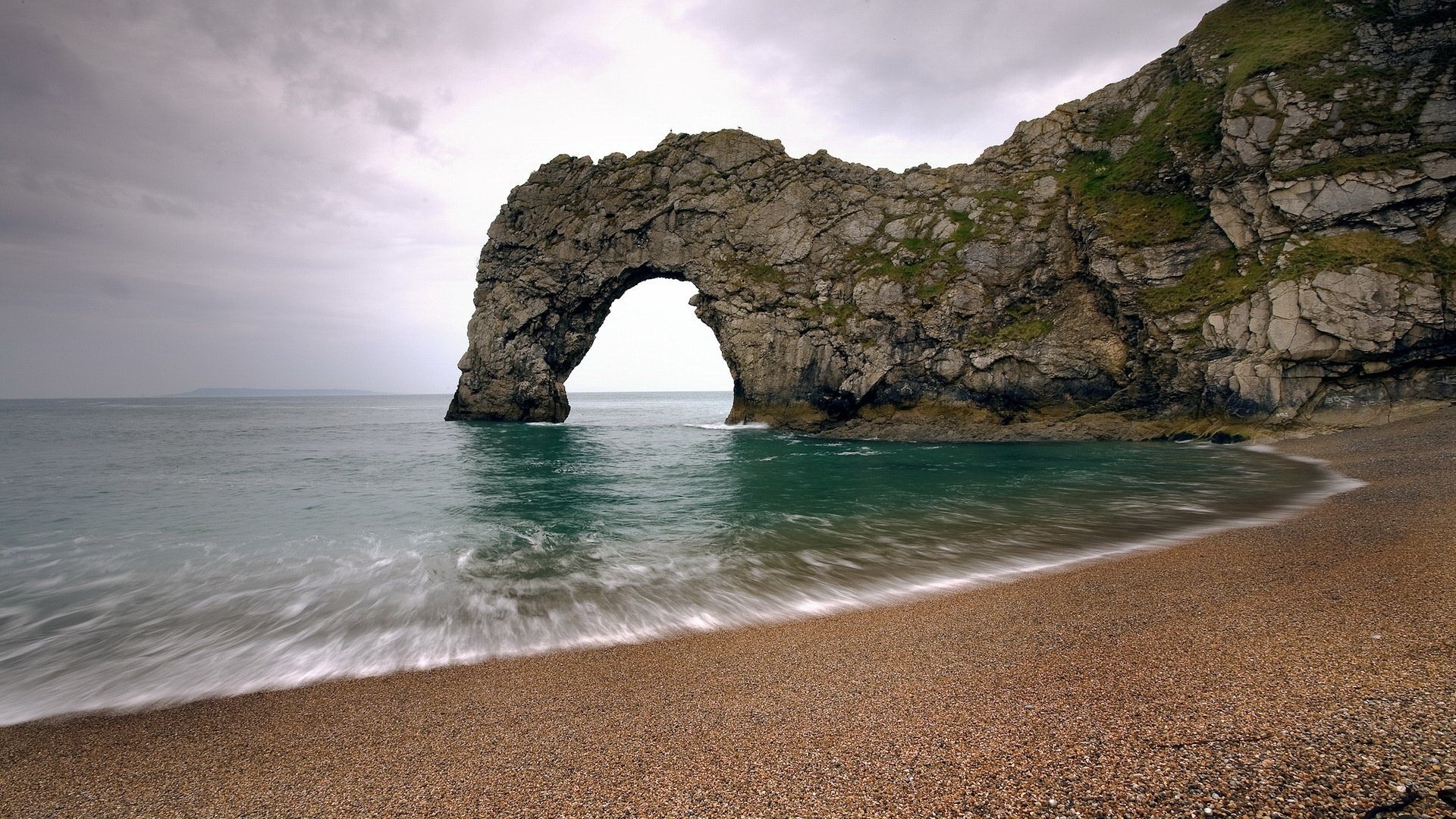 arche dans la roche roches mer plage eau côte vagues surf horizon nature nuageux arche roches eau verte sable