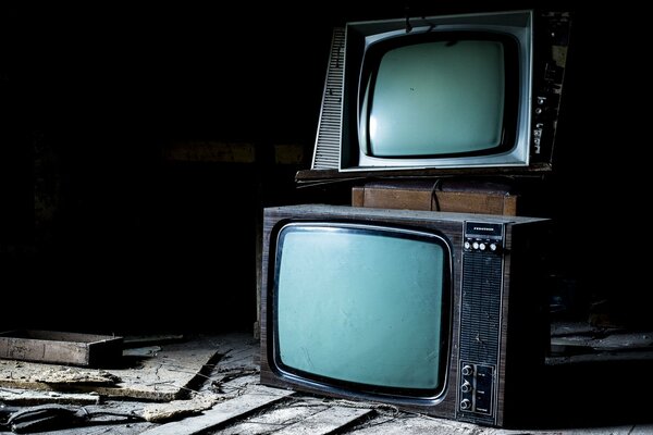 На полу стоят старые телевизоры друг на друге