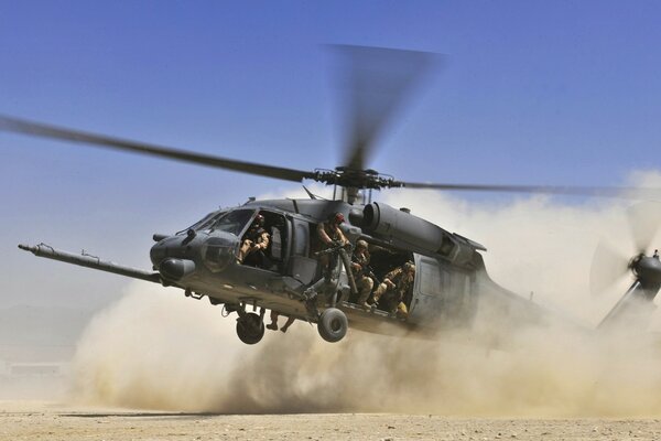 Helicóptero aterriza en el desierto levantando polvo