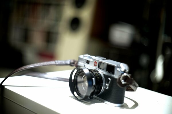 Fotocamera nera e argento con cravatta su superficie bianca