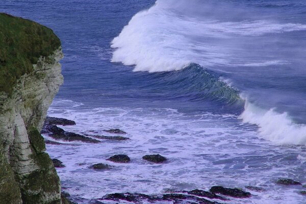 A foam wave in a storm hits the rocks nature