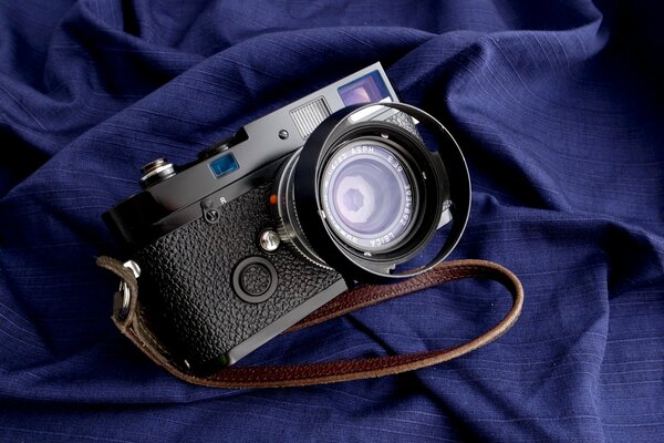 A camera with a strap on a blue canvas