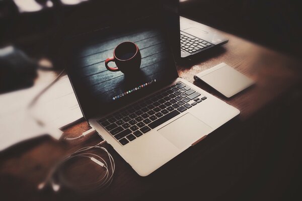 Laptop with headphones on the table with an image of a cup on the screen