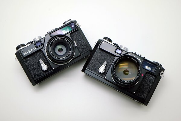 Чёрные фотоаппараты Nikon на белом фоне