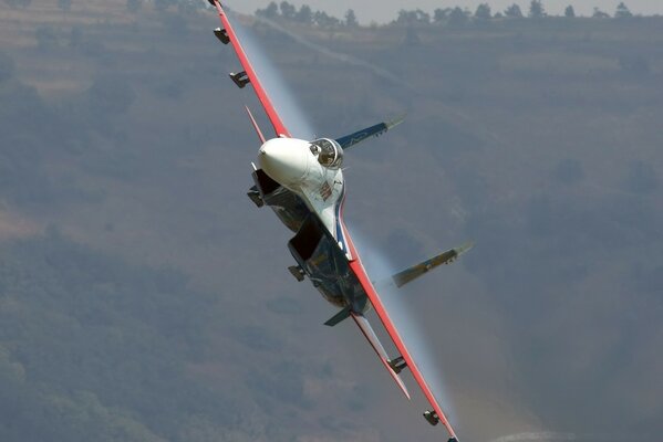 The Su-27 fighter soars among the mountains