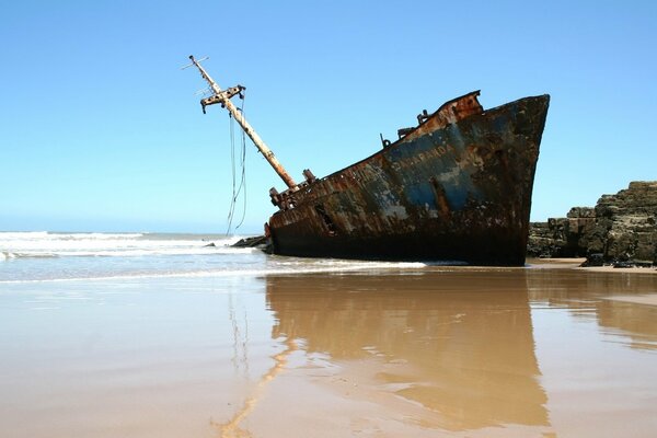 Boot im Sand vor dem Hintergrund von klarem Himmel und Wasser