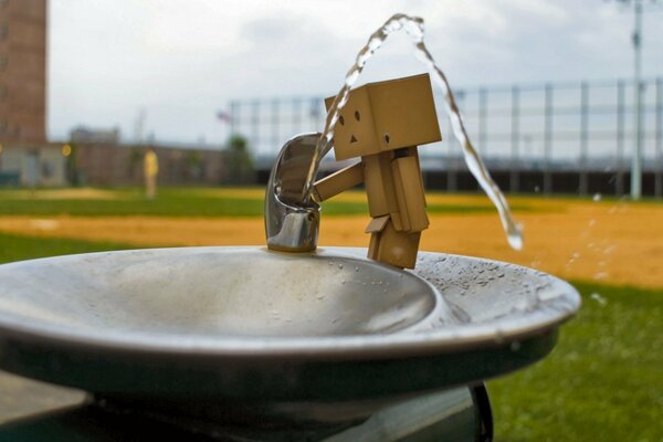 The boxman drinks water from a fountain