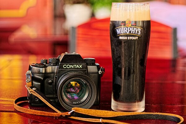 Macchina fotografica sul tavolo con un bicchiere di birra